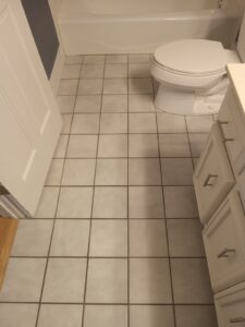 Dirty and cracked bathroom floor grout before restoration in Wheaton Illinois