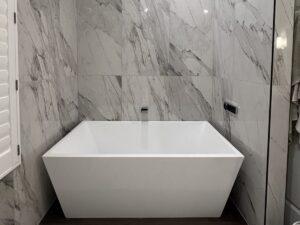 Bathroom remodel with a freestanding tub and large-format marble-look wall tile